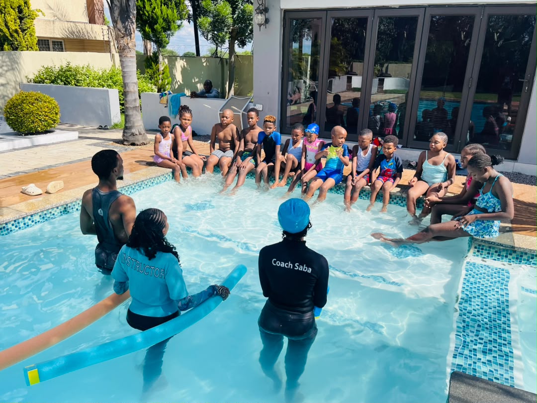 AquaMasters coaches briefing a group of children poolside before a lesson